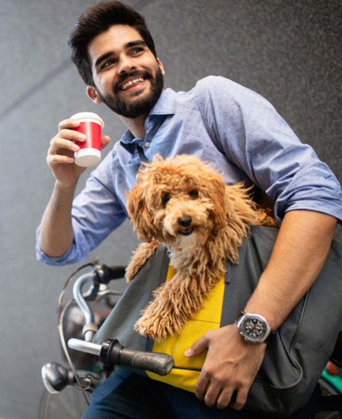 Man leaning on bike who is drink his coffee and holding his dog