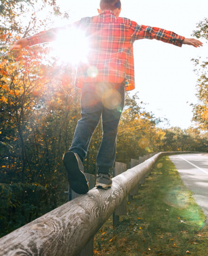 Young boy balancing on wooden guardrail