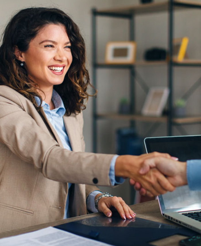 Smiling woman sitting at desk shaking hands
