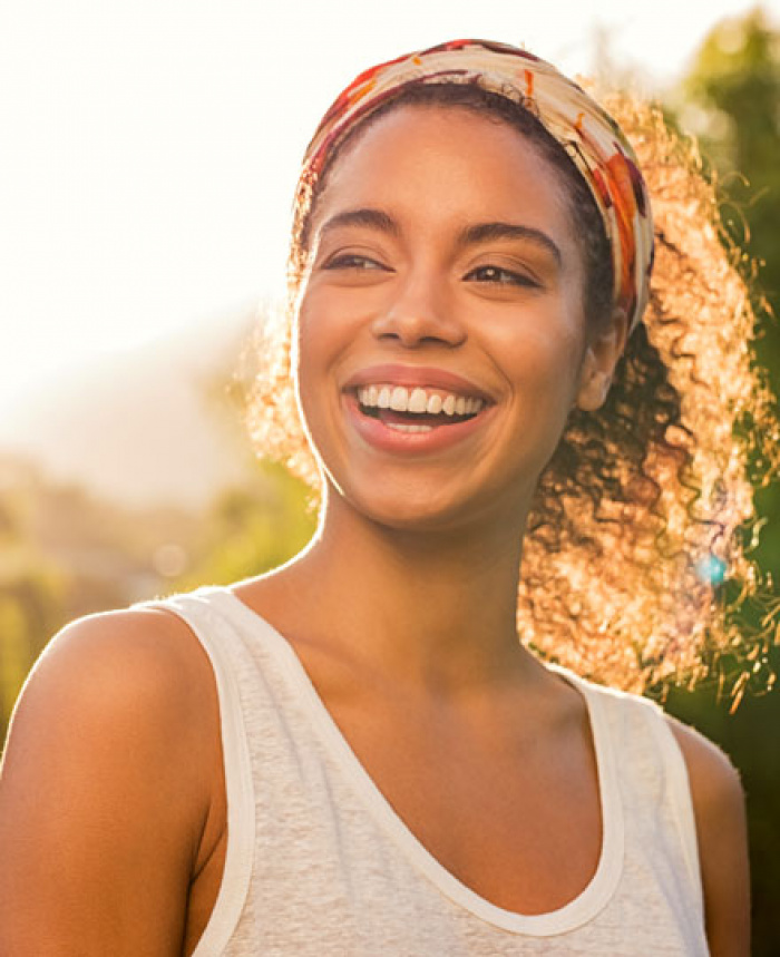 Woman outside smiling with sun rising behind her