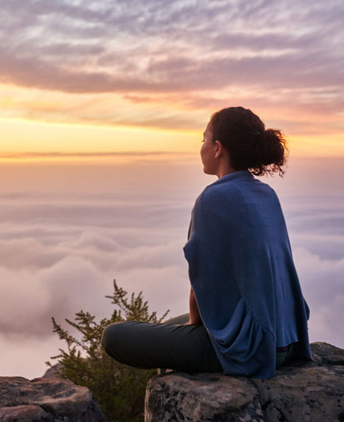 Woman sitting on mountain at sunrise